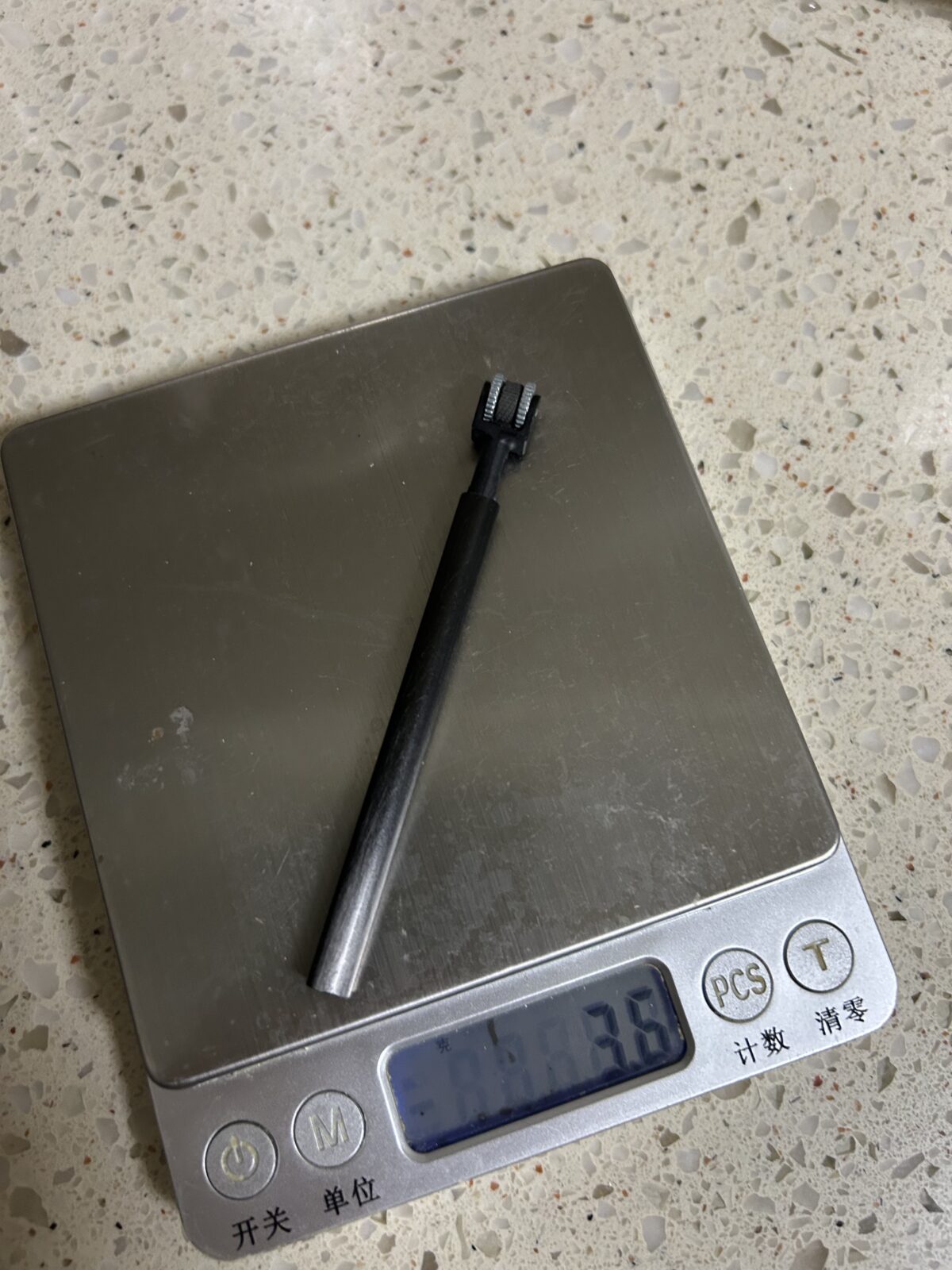 一支金属筒状轻量化户外打火器放在电子秤上，显示重量为3.6克。